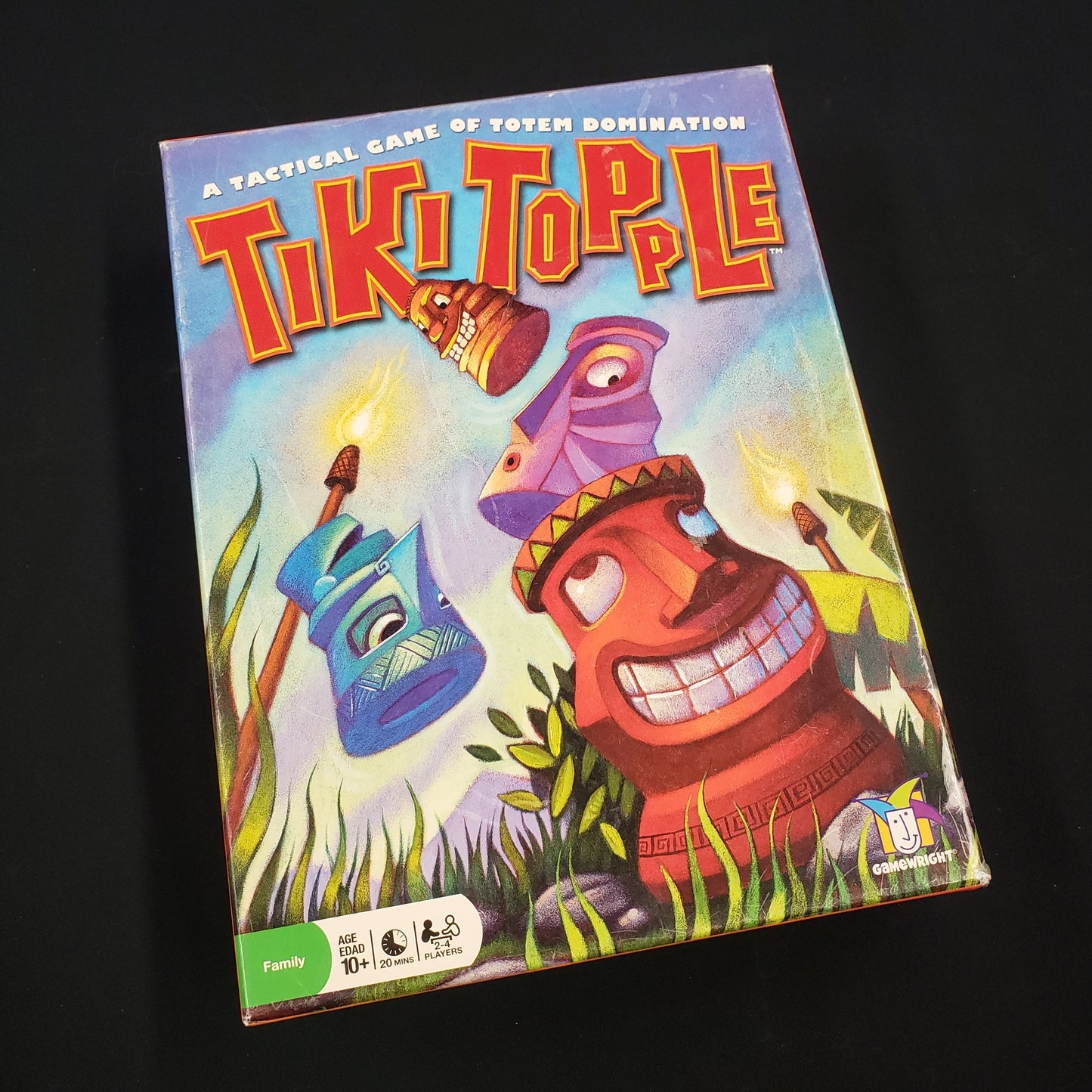 Image shows the front cover of the box of the Tiki Topple board game