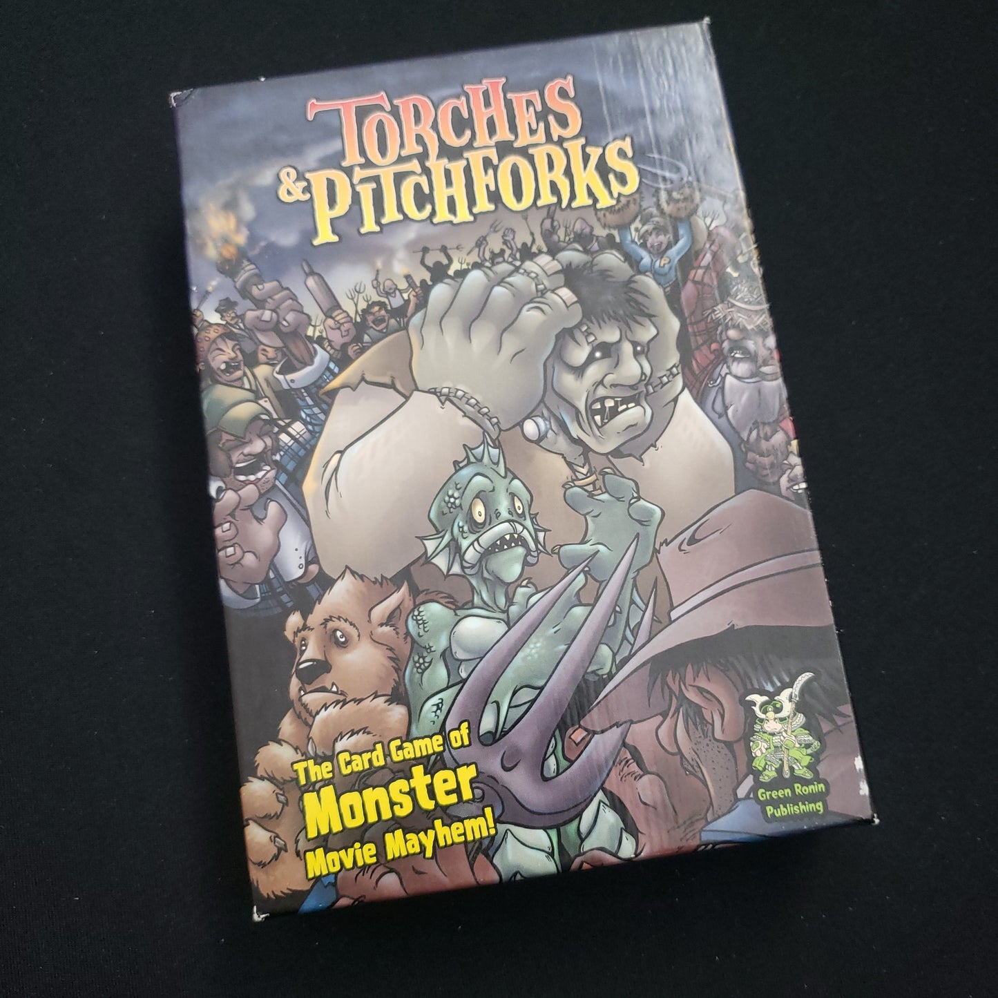 Image shows the front cover of the box of the Torches and Pitchforks card game