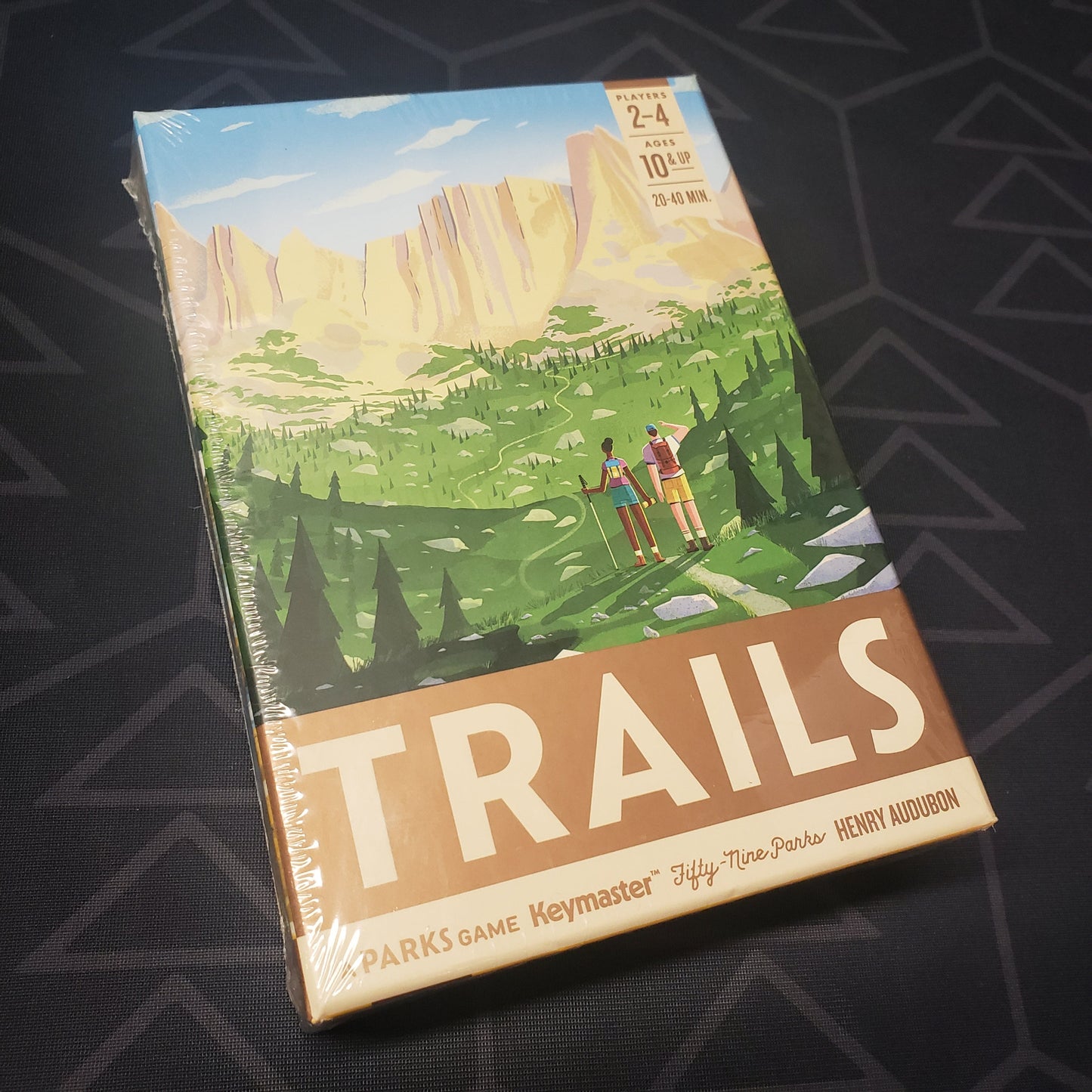 Image shows the front cover of the box for the Trails board game