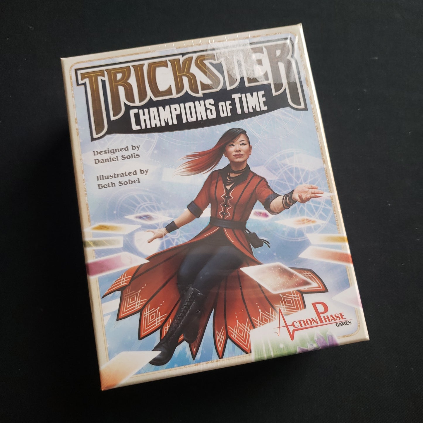 Image shows the front cover of the box of the Trickster: Champions of Time card game