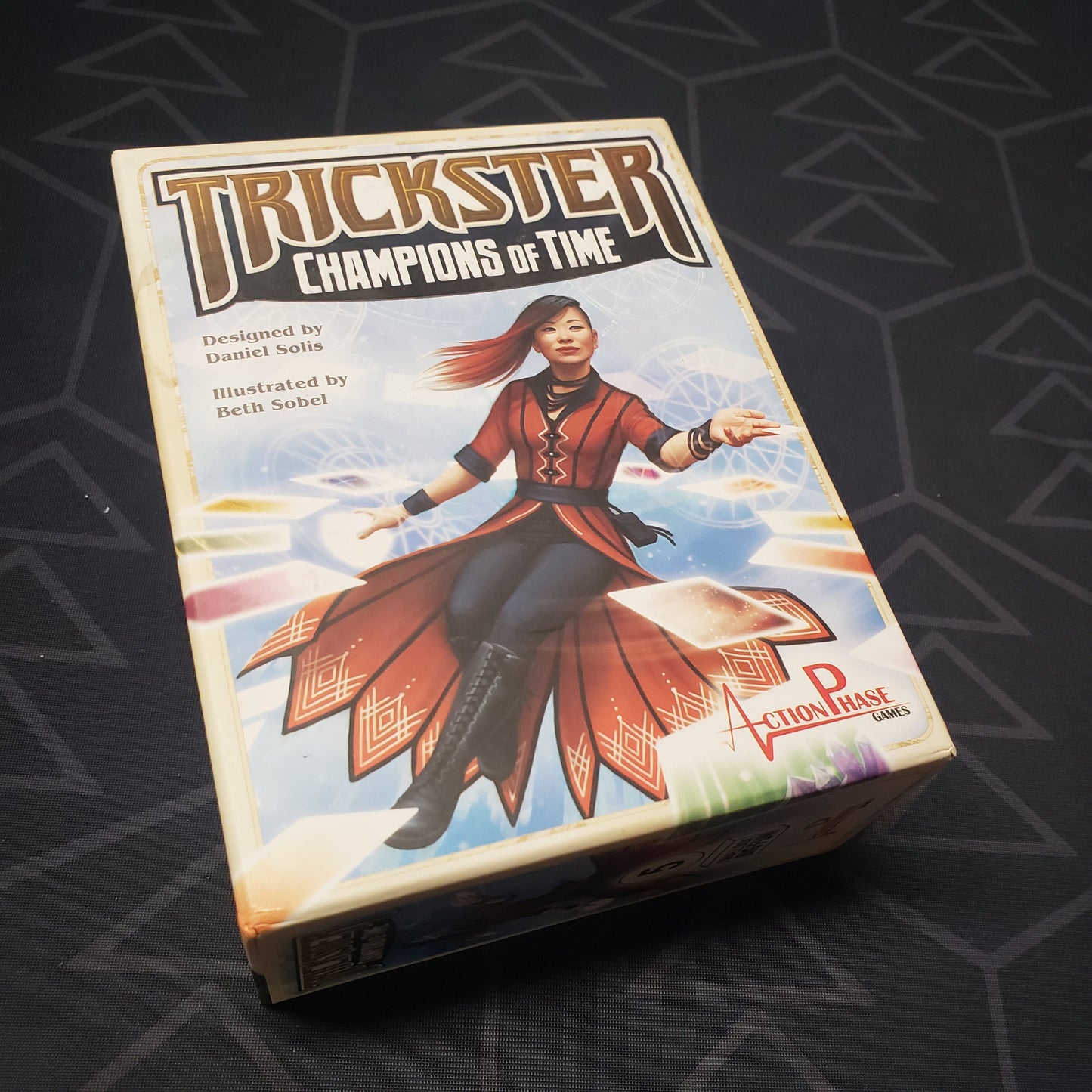 Image shows the front cover of the box of the Trickster: Champions of Time card game