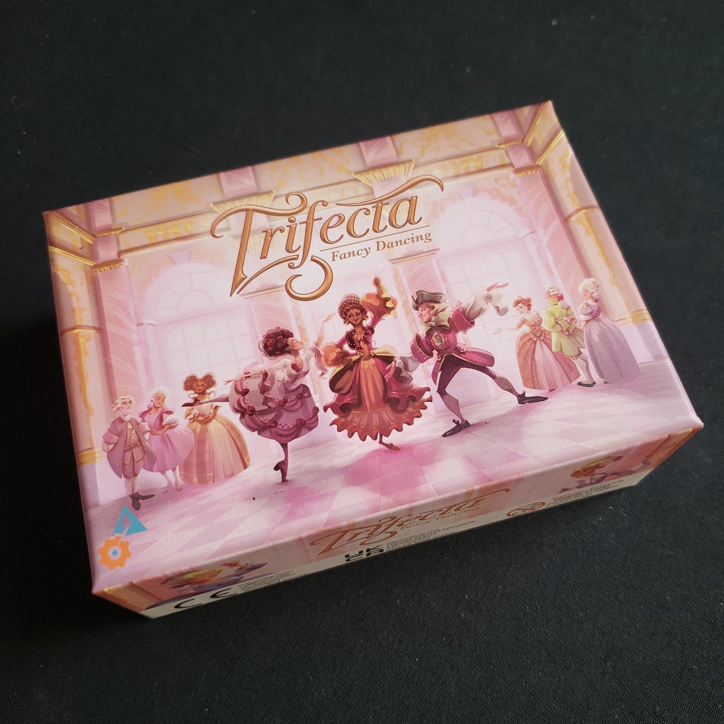 Image shows the front cover of the box of the Trifecta: Fancy Dancing card game