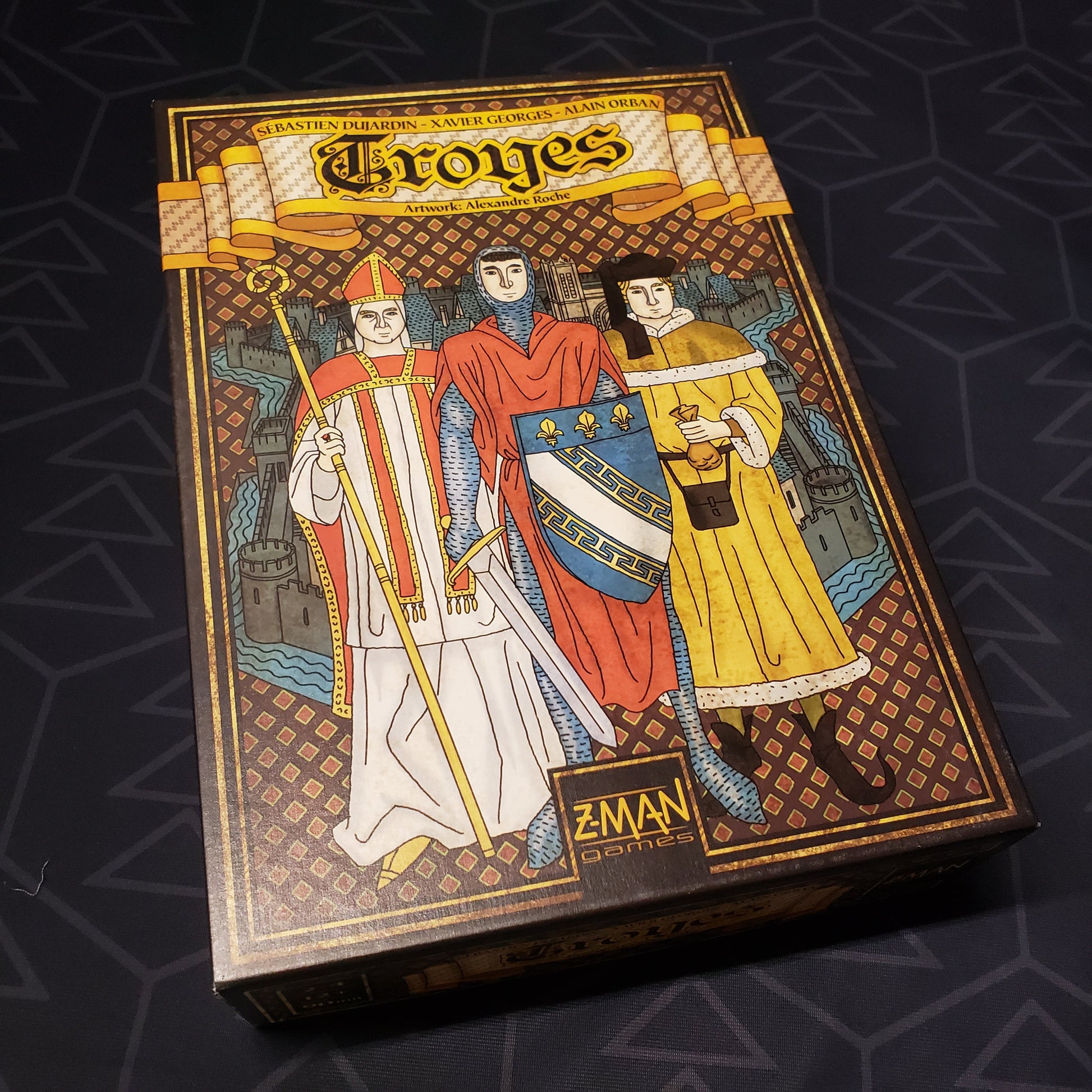 Image shows the front cover of the box of the Troyes board game