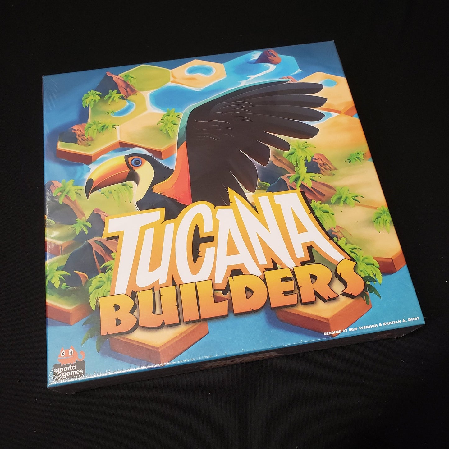 Image shows the front cover of the box of the Tucana Builders board game