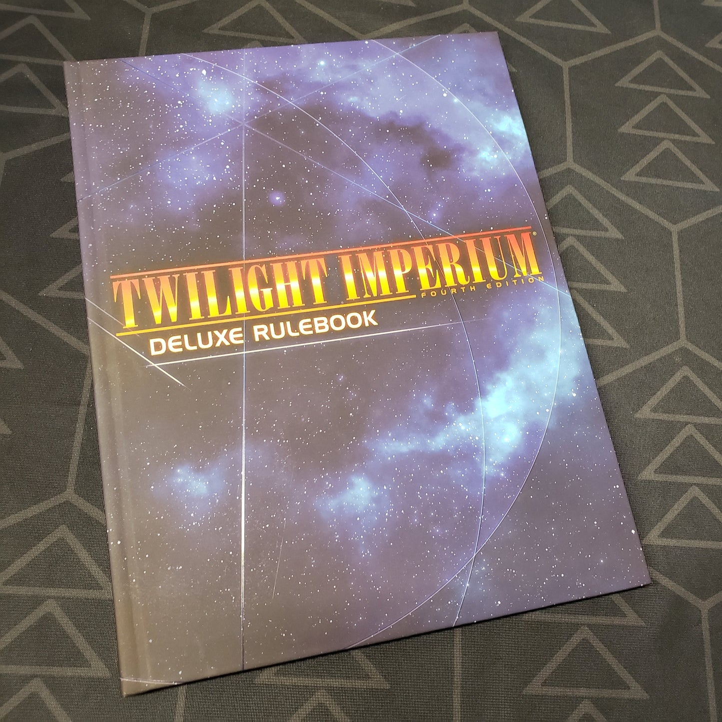 Image shows the front cover of the Deluxe Rulebook for the board game Twilight Imperium (Fourth Edition)