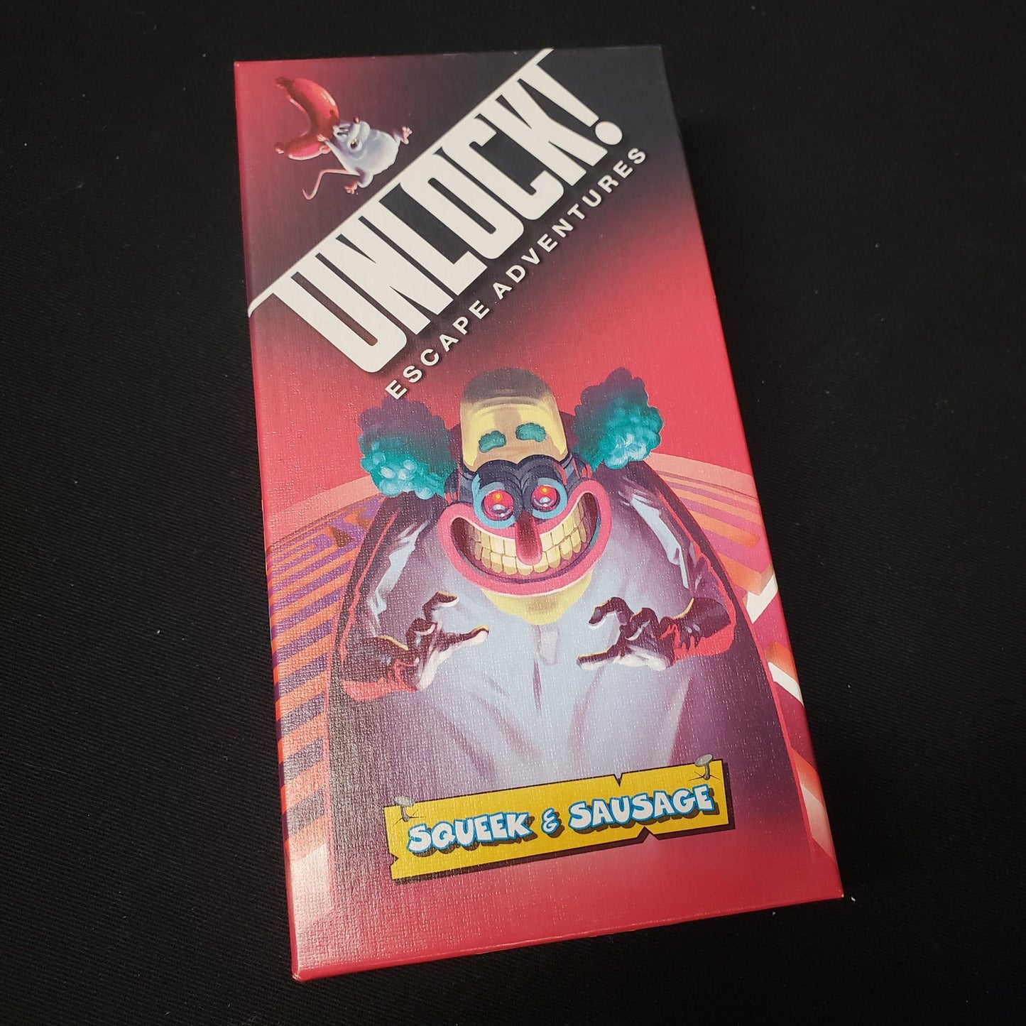 Image shows the front cover of the box of the Unlock!: Squeek & Sausage card game