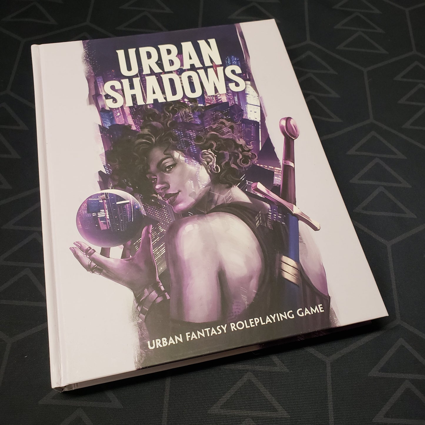 Image shows the front cover of the core rulebook for the roleplaying game Urban Shadows: Second Edition