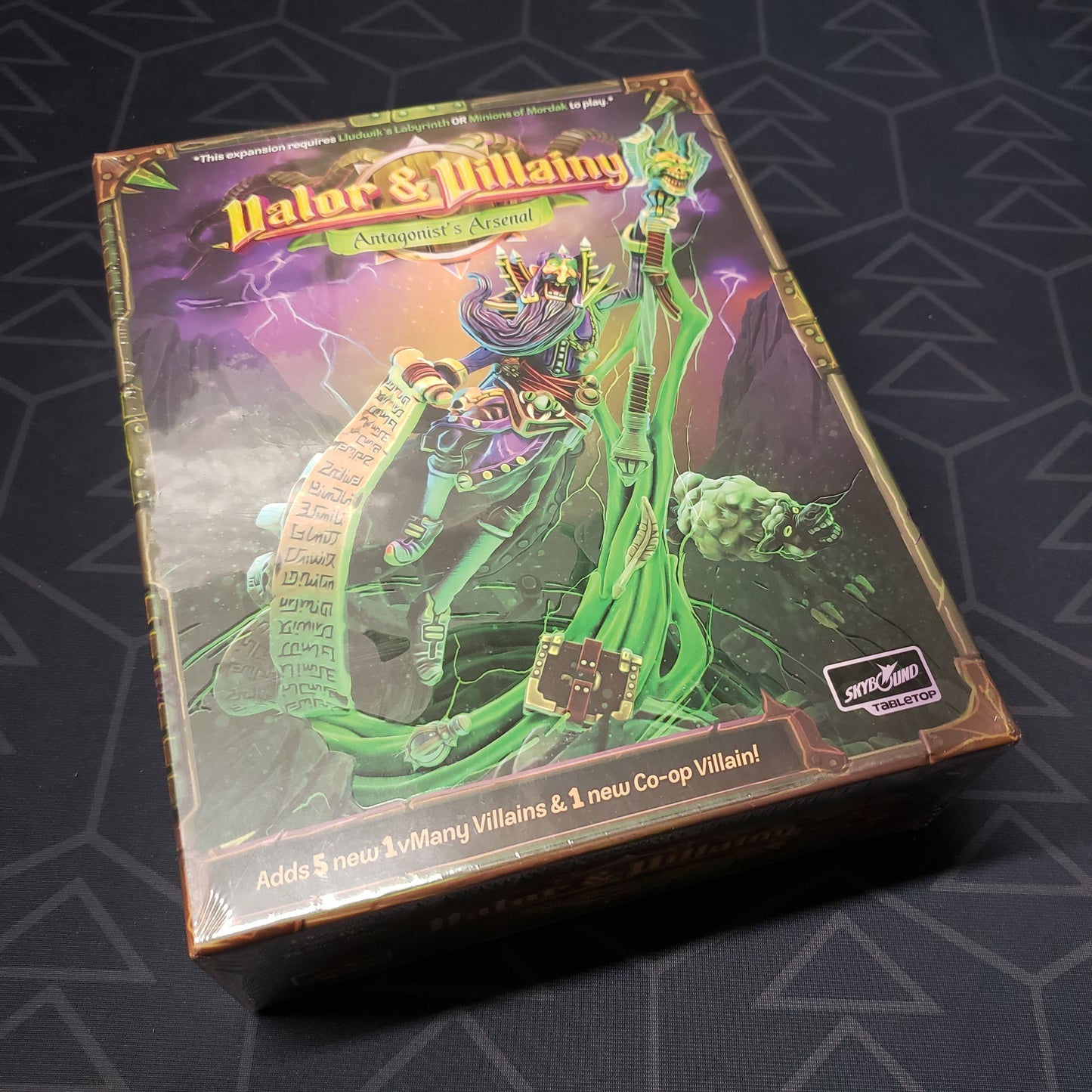 Image shows the front cover of the box of the Antagonist's Arsenal expansion for the board game Valor & Villainy