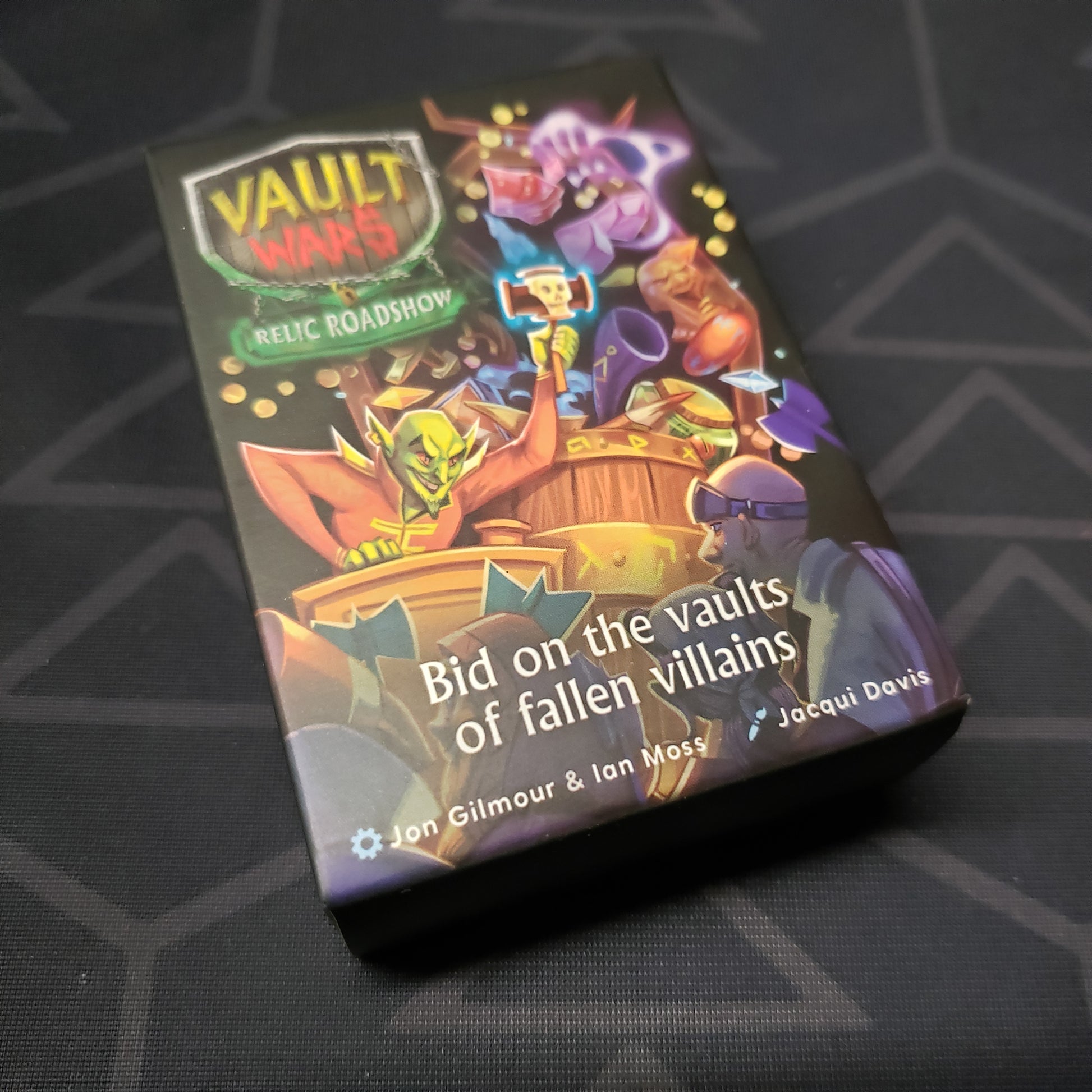 Image shows the front cover of the box of the Relic Roadshow expansion for the card game Vault Wars