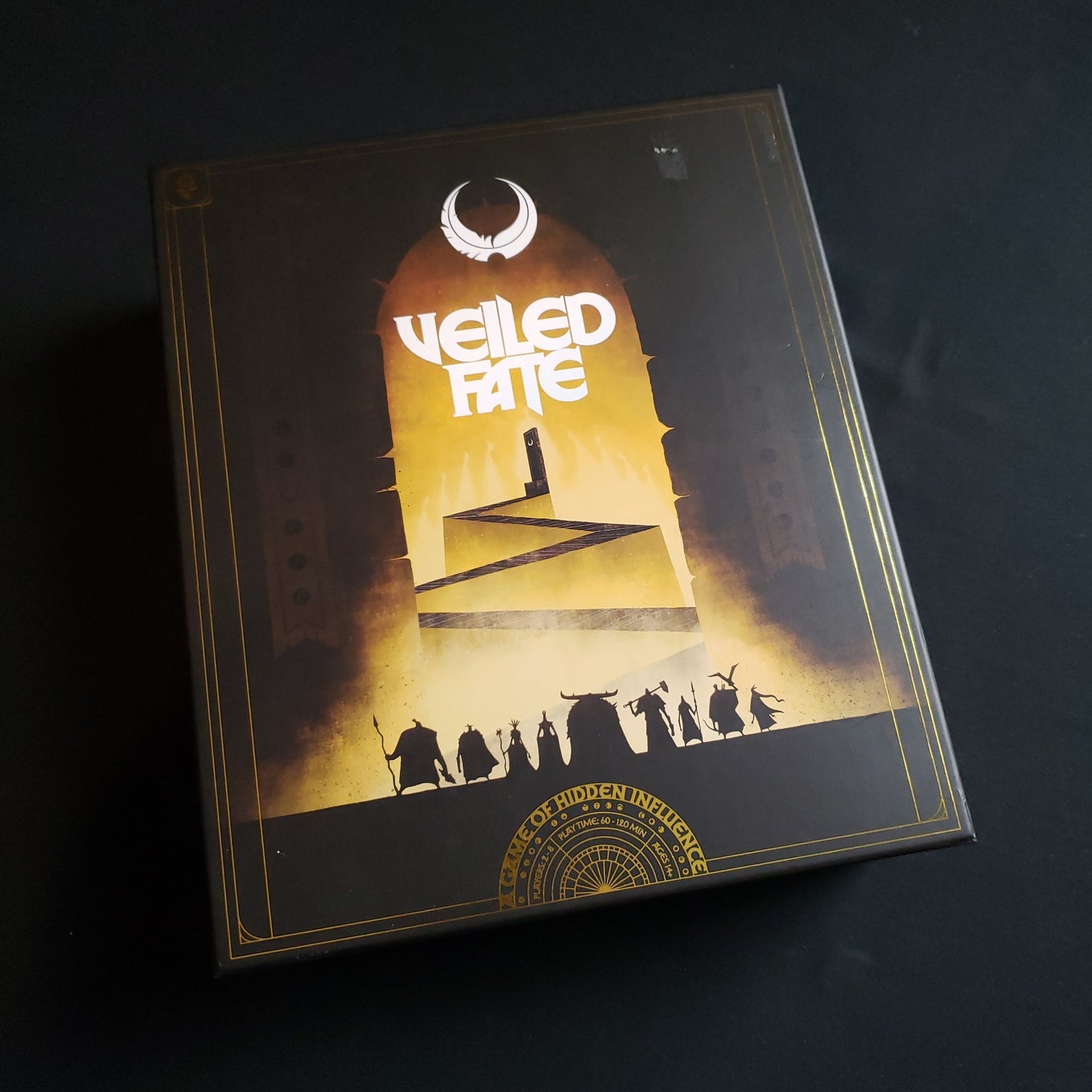 Image shows the front cover of the box of the Veiled Fate board game