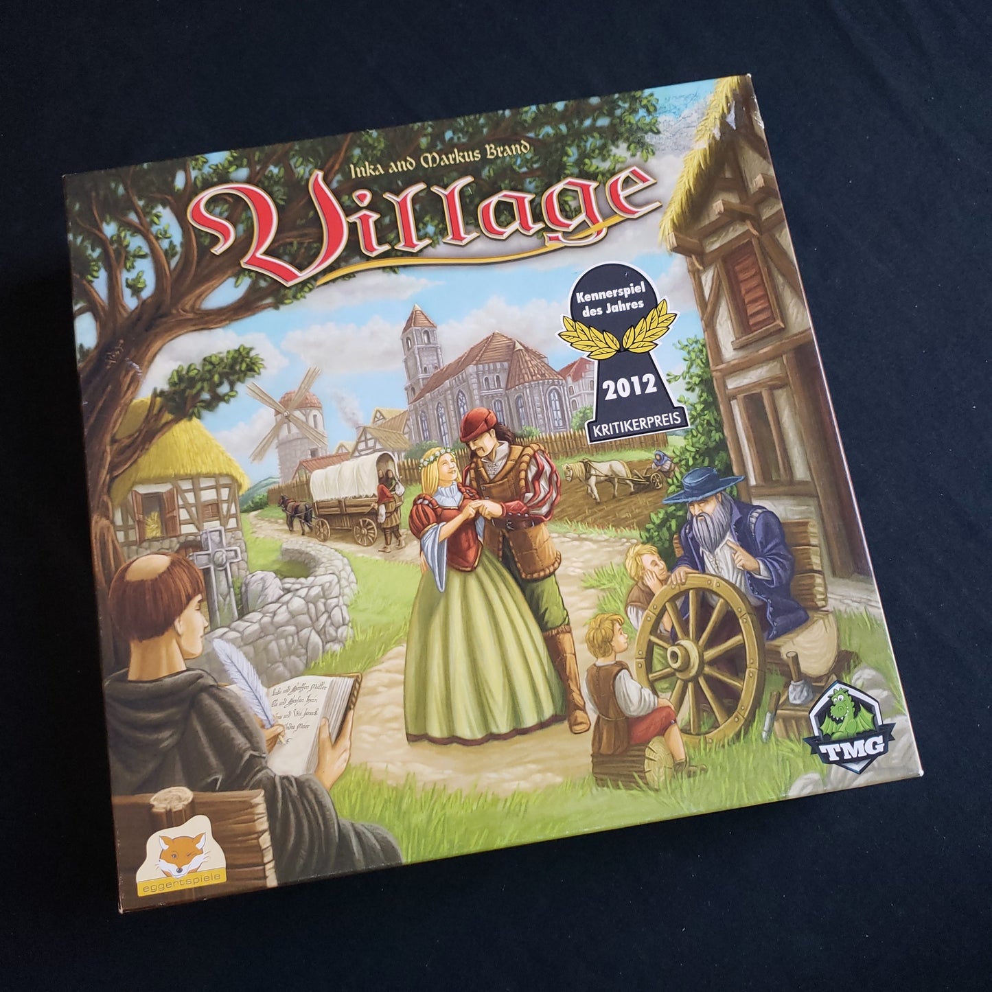 Image shows the front cover of the box of the Village board game