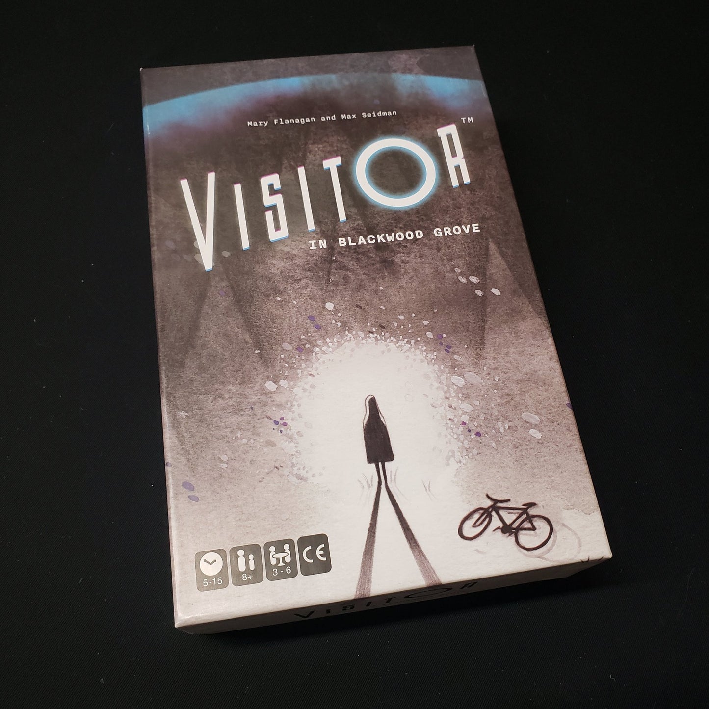 Image shows the front cover of the box of the Visitor in Blackwood Grove board game