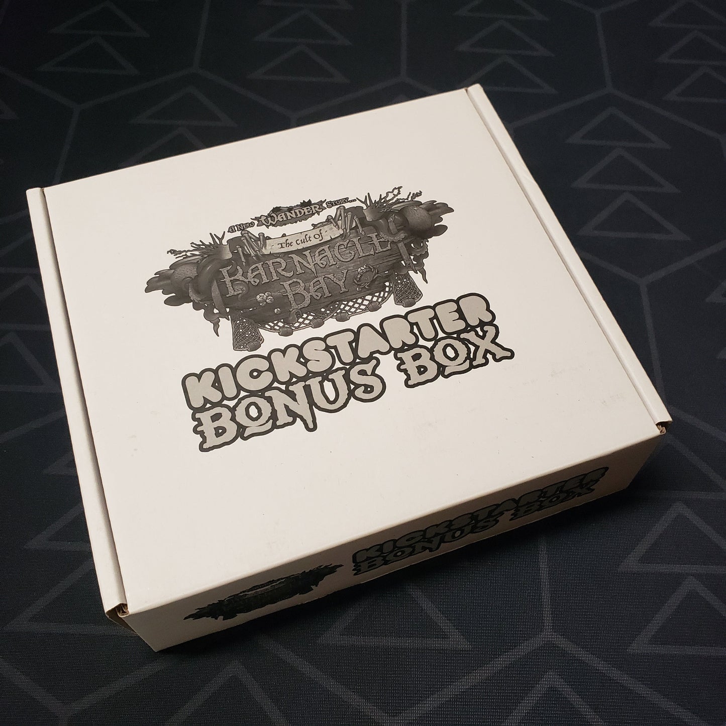 Image shows the front cover of the box of the Kickstarter Bonus Box expansion for the board game Wander: The Cult of Barnacle Bay