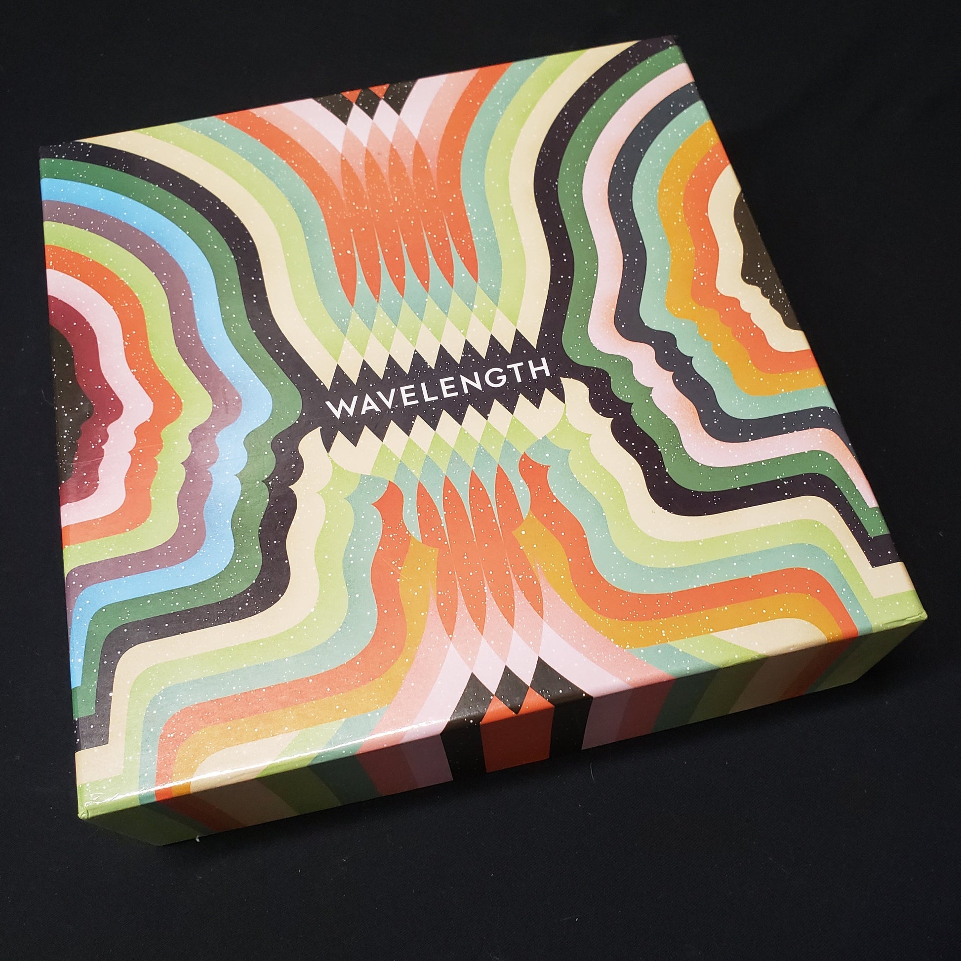 Image shows the front cover of the box of the Wavelength board game