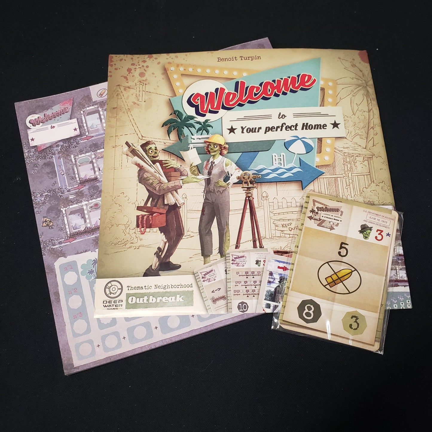 Image shows the score pad, instruction sheet and cards for the Outbreak expansion for the board game Welcome To…