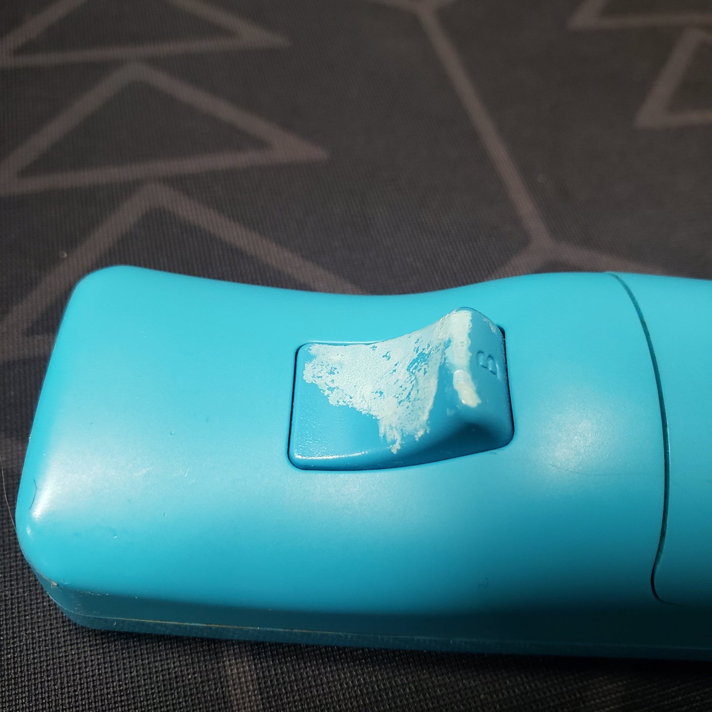 Image shows the B-trigger button of a blue MotionPlus controller for Nintendo Wii