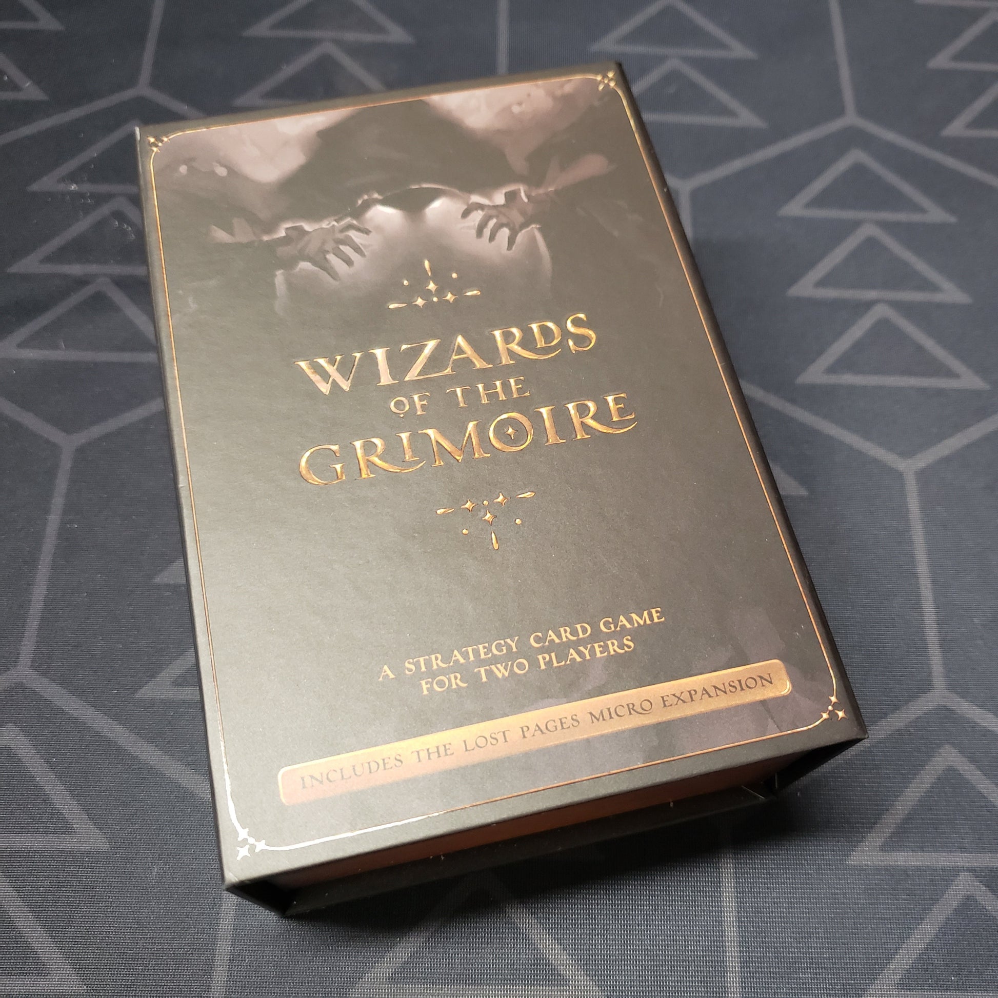 Image shows the front cover of the box of the Wizards Of The Grimoire card game