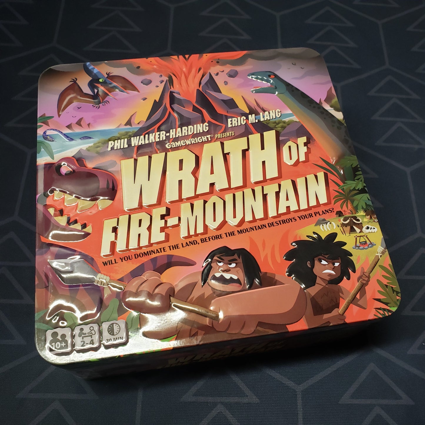 Image shows the front cover of the tin box for the Wrath of Fire Mountain board game