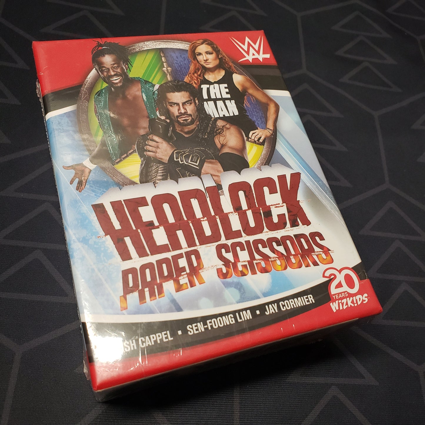 Image shows the front cover of the box of the WWE Headlock Paper Scissors card game
