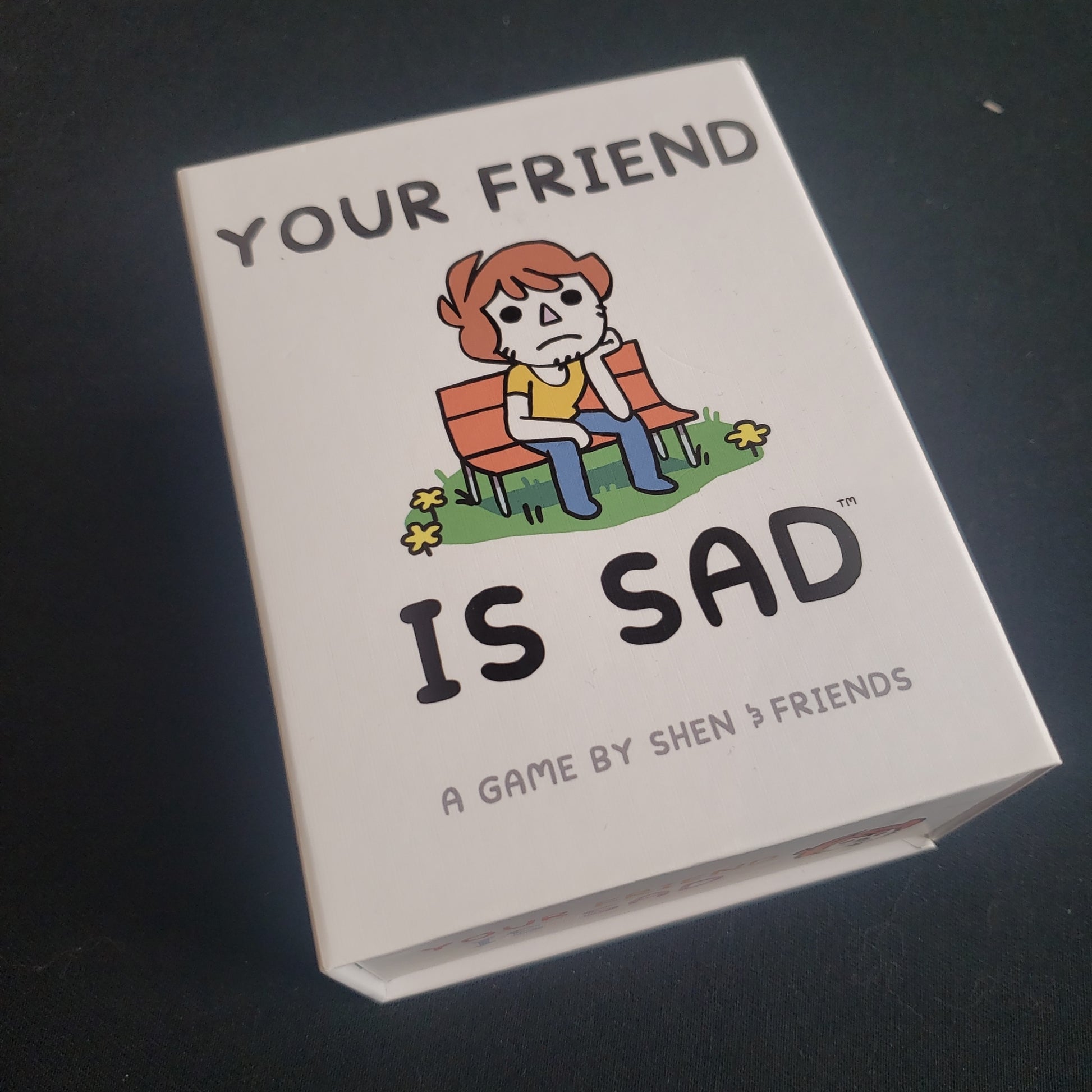 Image shows the front cover of the box of the Your Friend Is Sad card game