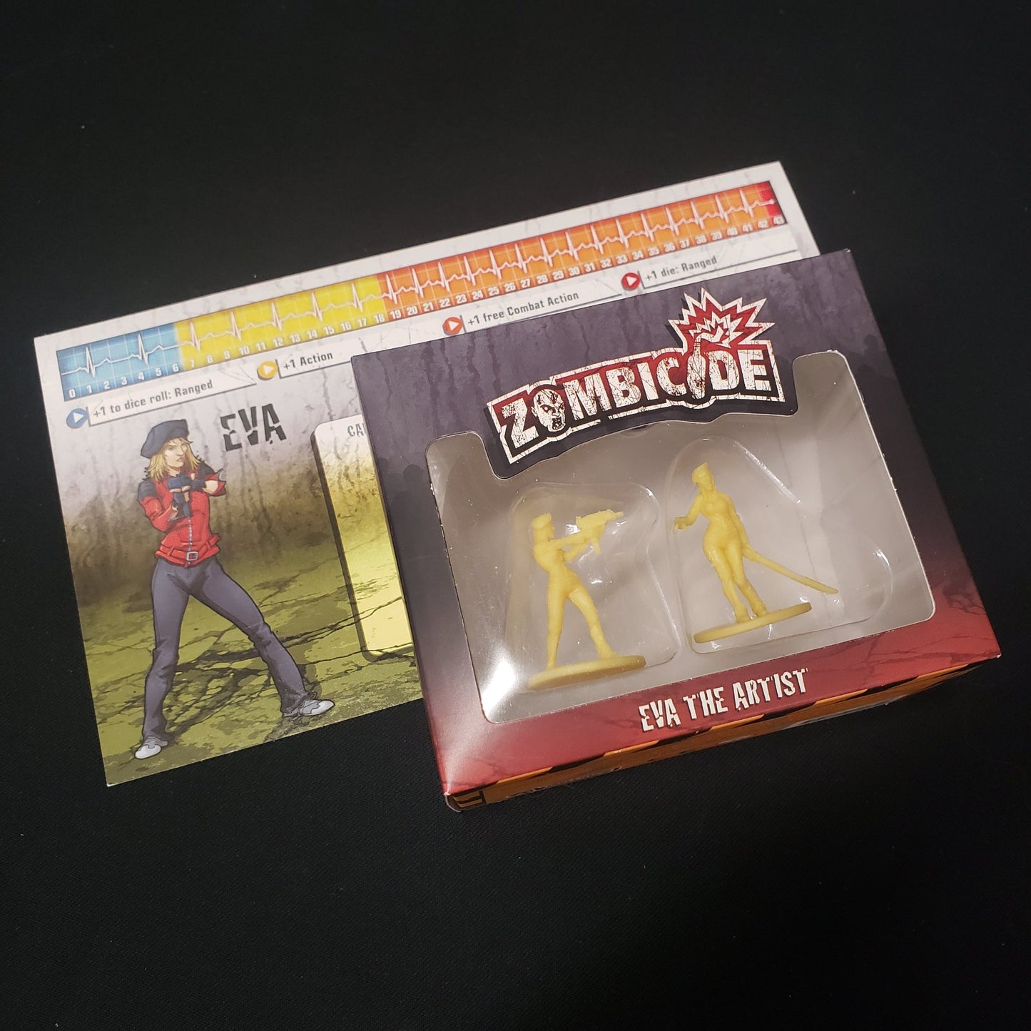 Image shows the front cover of the box & character dashboard for the Eva the Artist expansion for the board game Zombicide