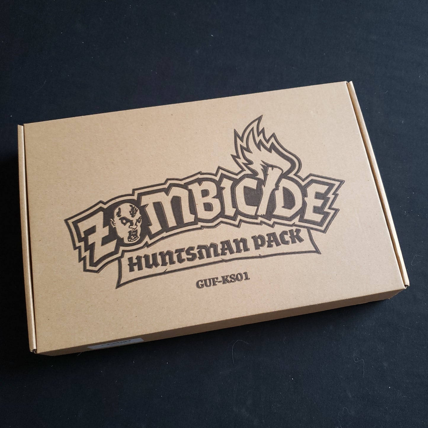 Image shows the front cover of the box of the Huntsman Pack expansion for the Zombicide: Black Plague board game