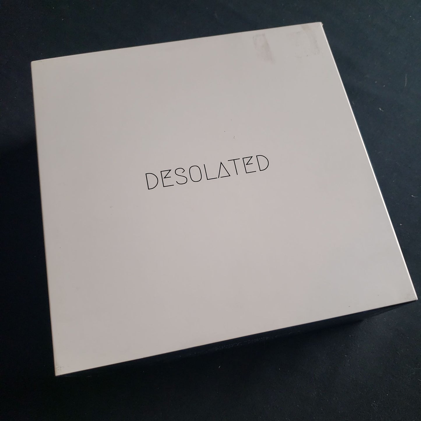Image shows the front cover of the box of the Desolated board game