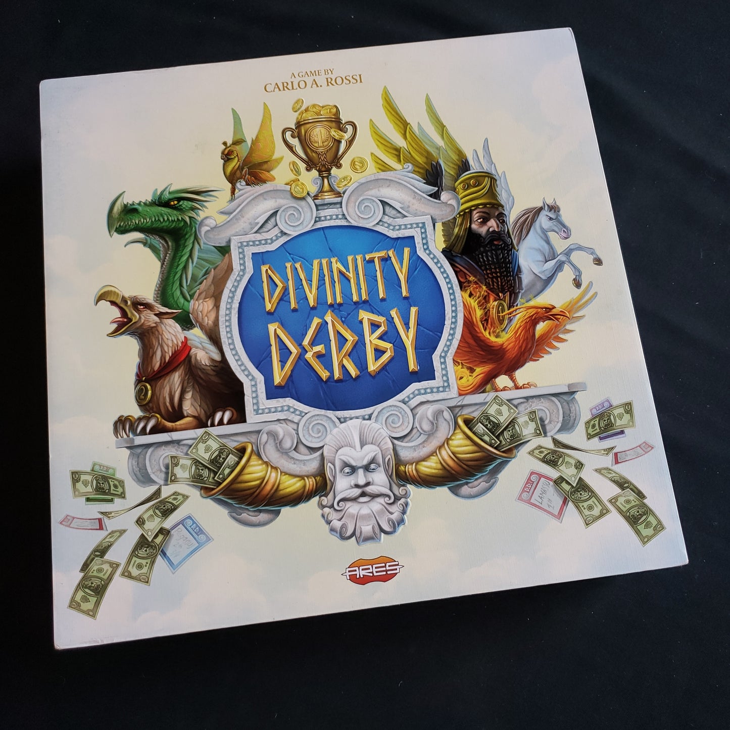 Image shows the front cover of the box of the Divinity Derby board game