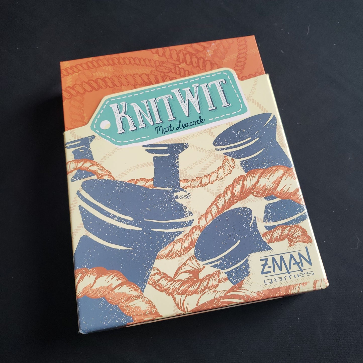 Image shows the front cover of the box of the Knit Wit board game