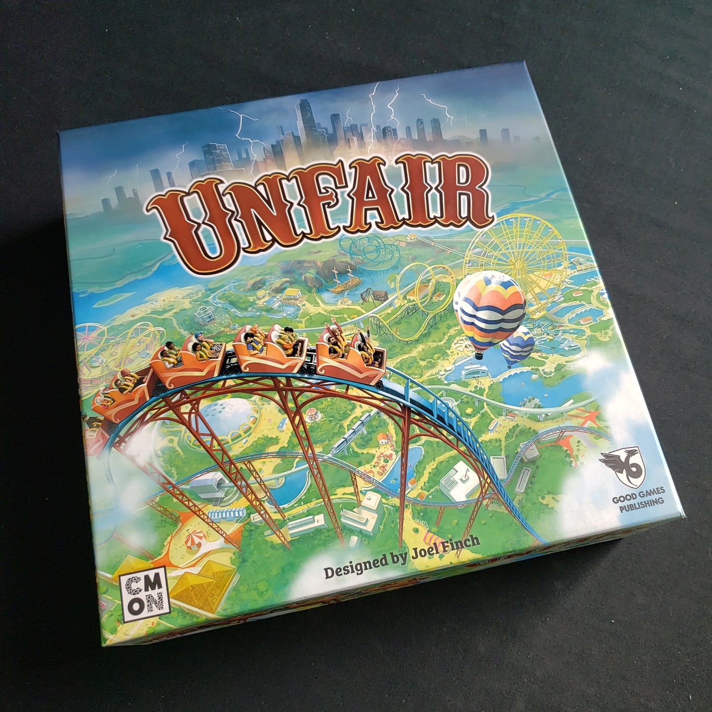 Image shows the front cover of the box of the Unfair board game