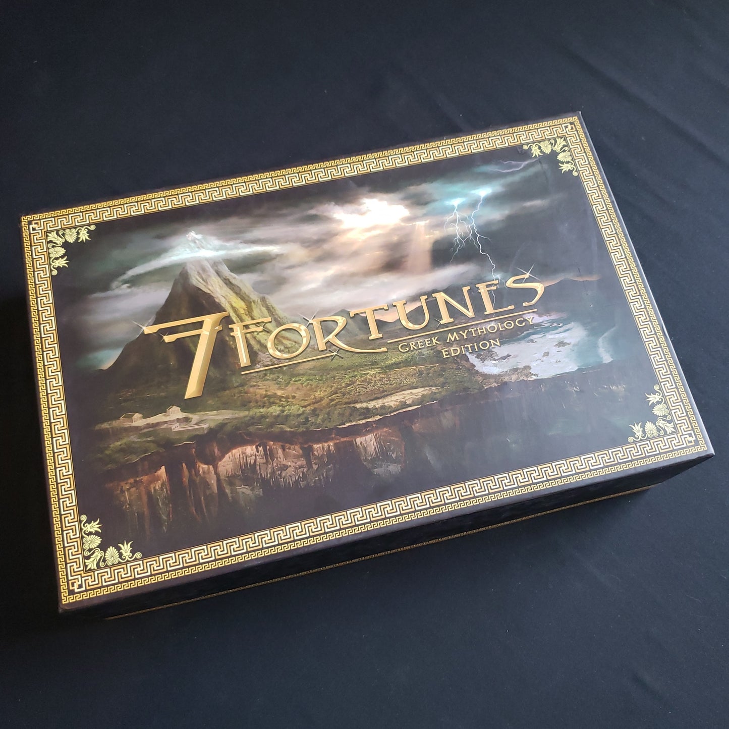 Image shows the front cover of the box of the Greek Mythology Edition of the board game 7 Fortunes