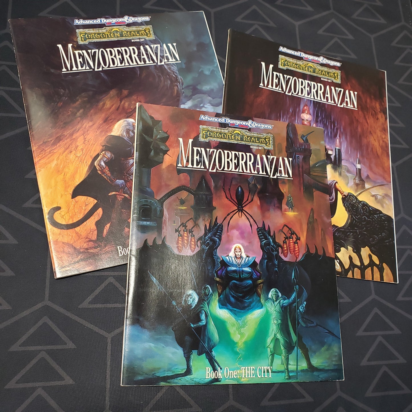 Image shows the front cover of the three books fanned out for the Forgotten Realms: Menzoberranzan set for the roleplaying game Advanced Dungeons & Dragons 2E