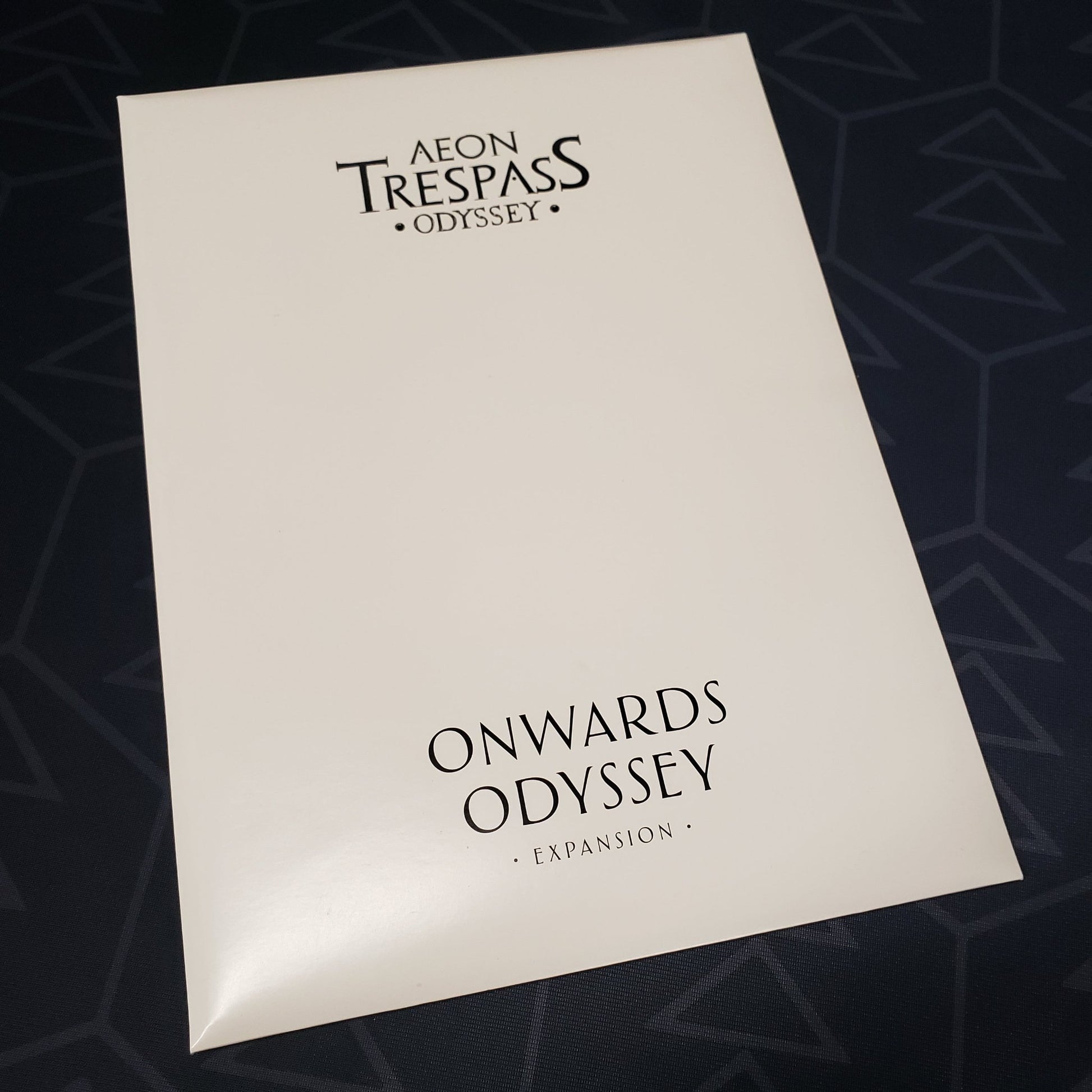 Image shows the front cover of the envelope of the Onwards Odyssey expansion for the board game Aeon Trespass Odyssey