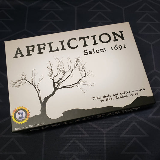 Image shows the front cover of the box of the Affliction: Salem 1692 board game