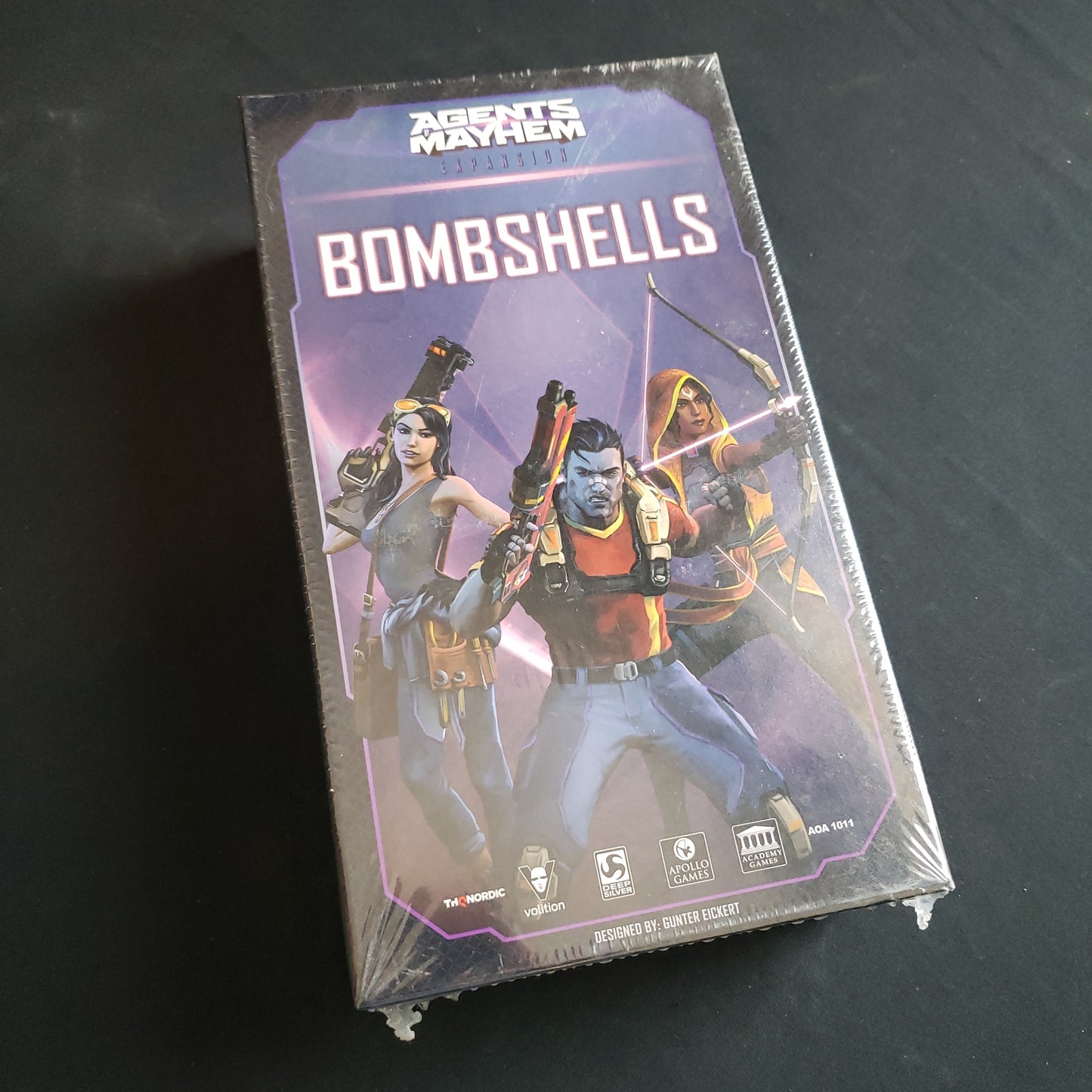 Image shows the front cover of the box of the Bombshells Team expansion for the board game Agents of Mayhem