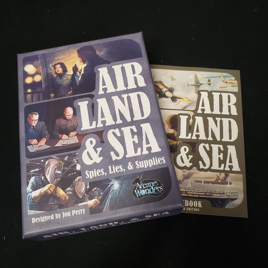 Image shows the front cover of the box of the Air, Land & Sea: Spies Lies & Supplies card game, sitting on top of the instructions for the original Air, Land & Sea game