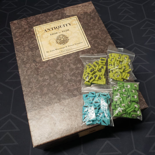 Image shows the front cover of the box of the board game Antiquity: Third Edition, with the GeekUp Bits pack sitting on top of it.