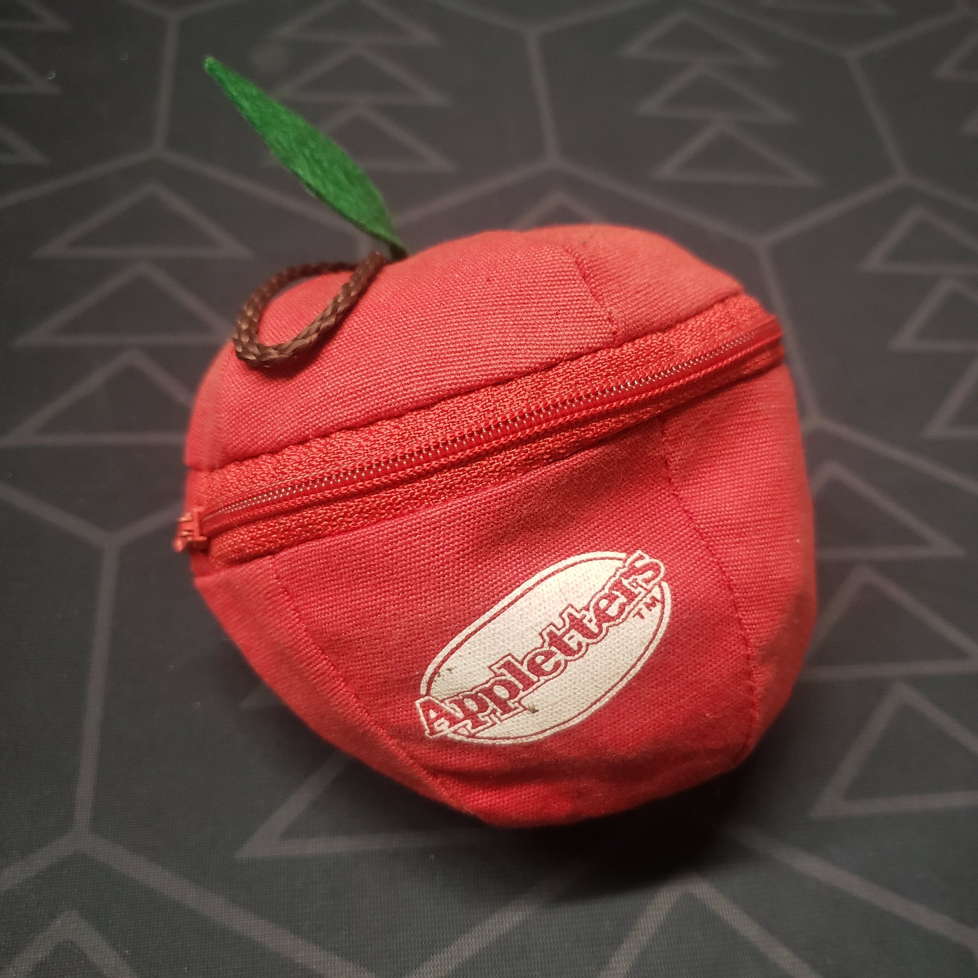 Image shows the outside of the apple-shaped zipper pouch for the Appletters board game
