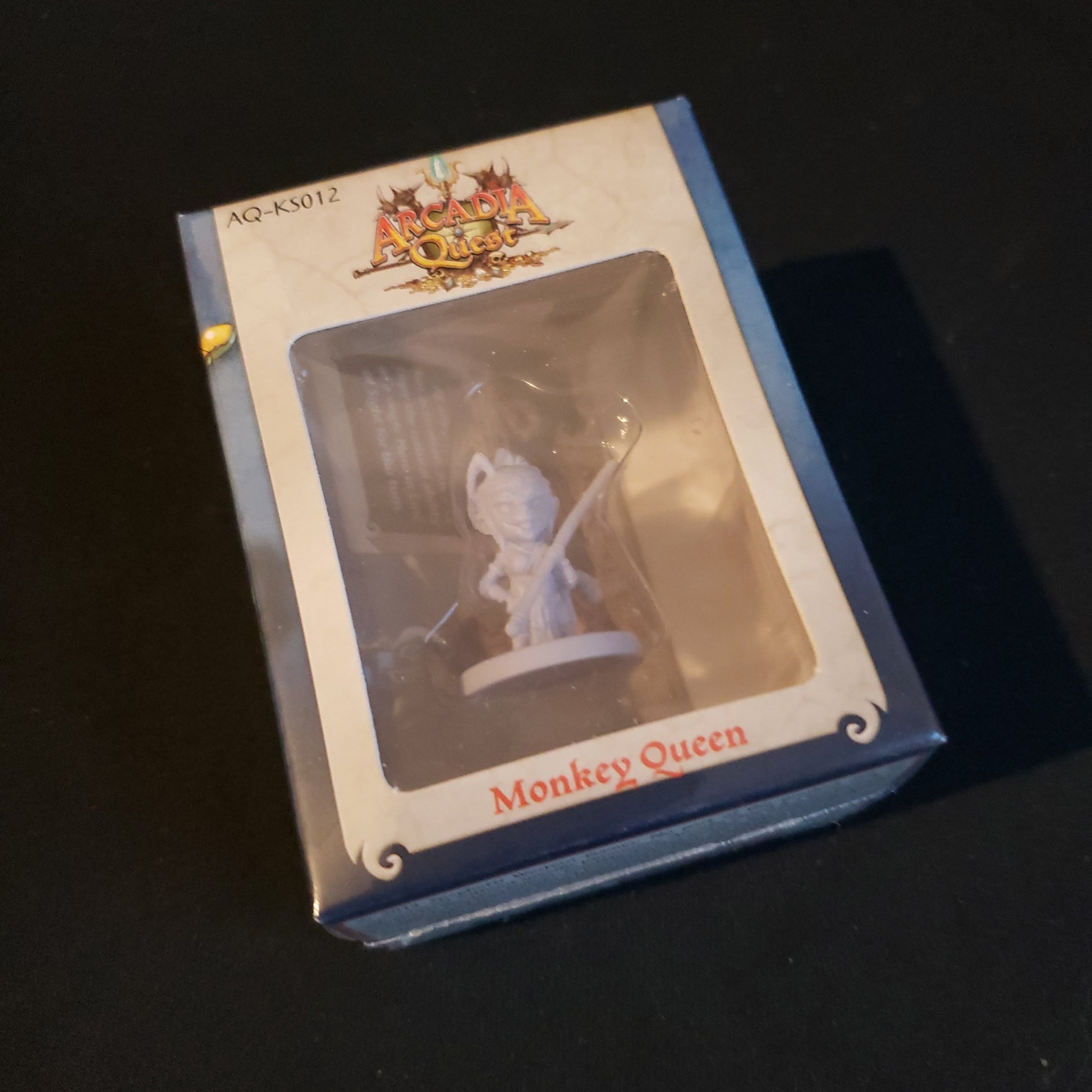 Image shows the front of the package for the Monkey Queen miniature pack for the Arcadia Quest board game