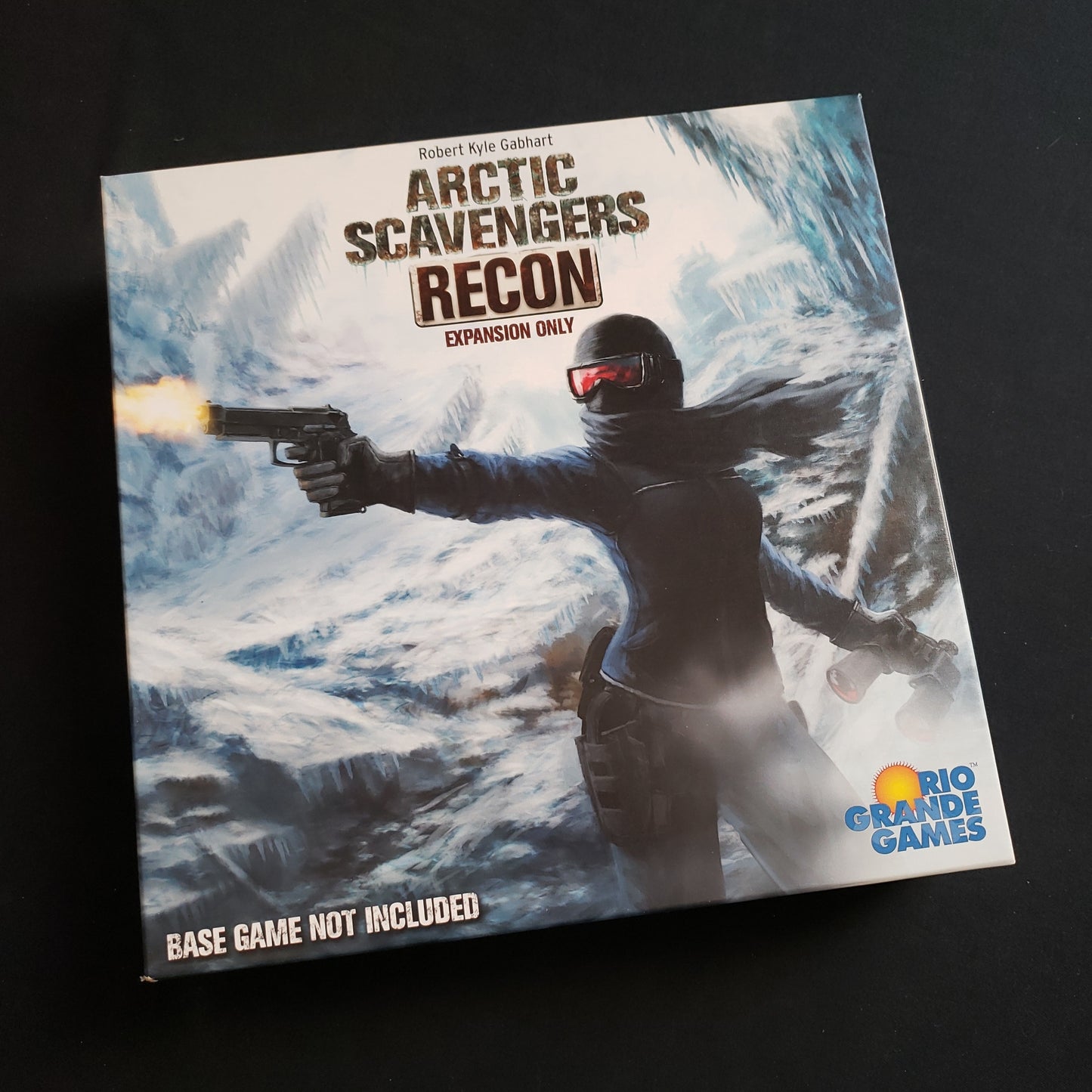 Image shows the front cover of the box of the Recon expansion for the card game Arctic Scavengers