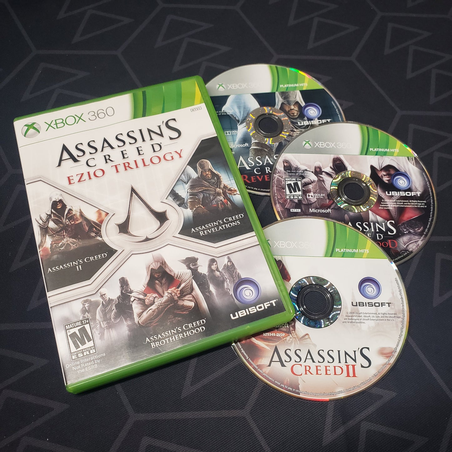 Image shows the case and three discs for the video game Assassin's Creed: Ezio Trilogy for Xbox 360