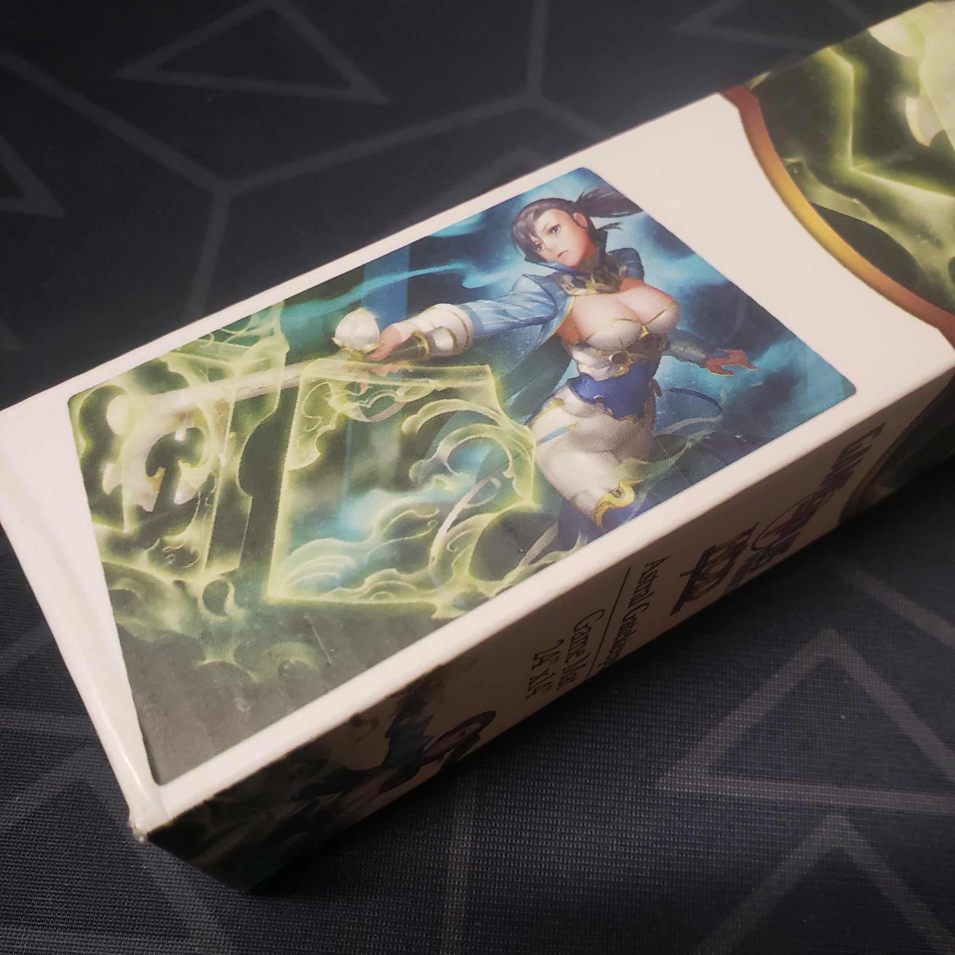 Image shows close-up of the art on the side of the box for the Astral Gatekeeper card game playmat