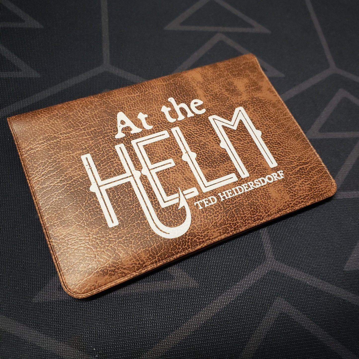 Image shows the front of the card wallet for the At the Helm card game