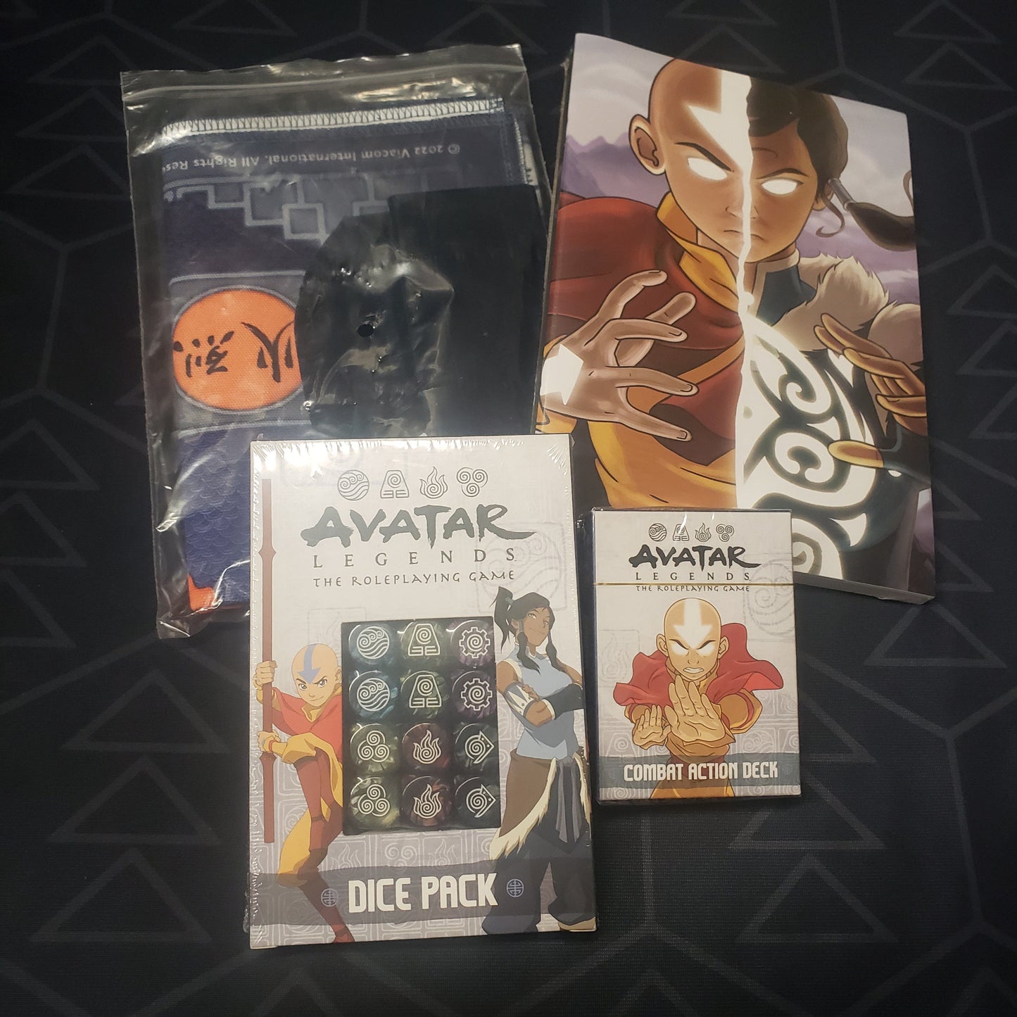 Image shows the various included accessories of the Kickstarter Stretch Goals Bundle for the roleplaying game Avatar Legends