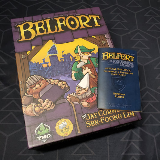 Image shows the front cover of the box of the Belfort board game with the expansion instructions sitting on top of it