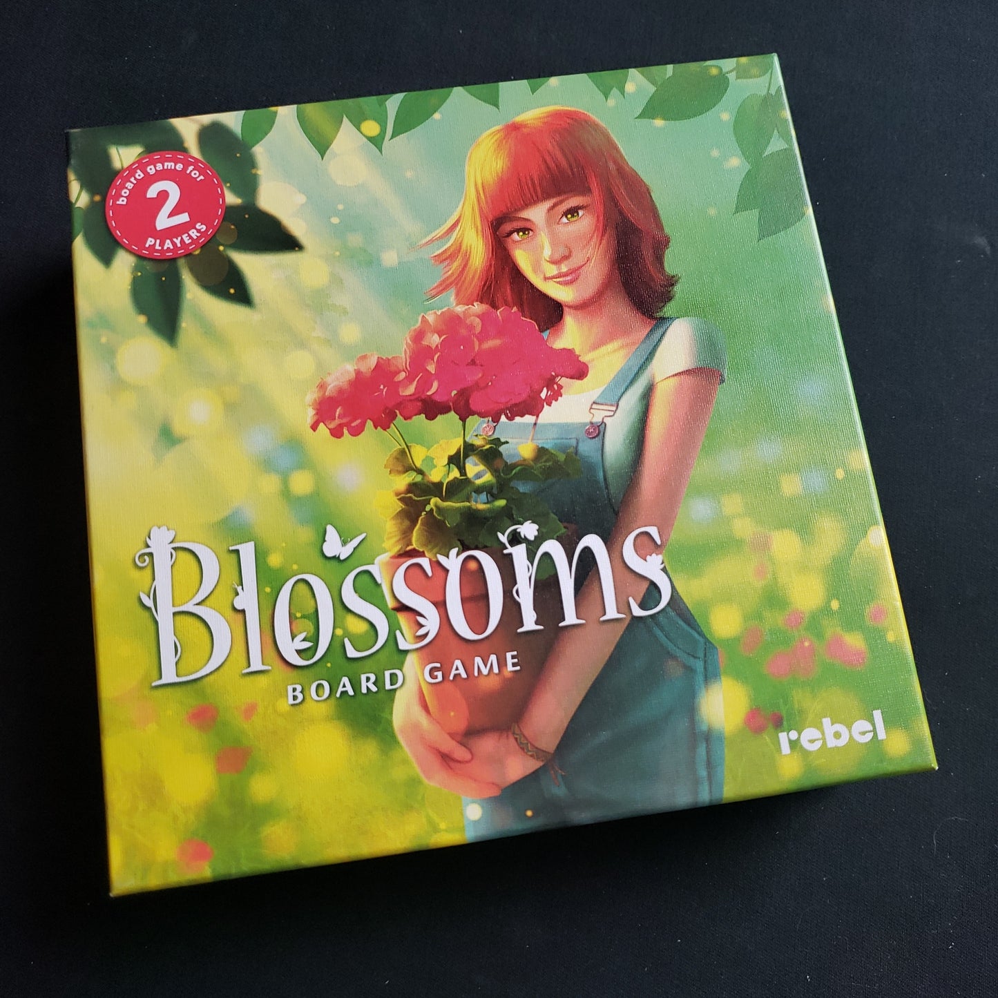 Image shows the front cover of the box of the Blossoms card game