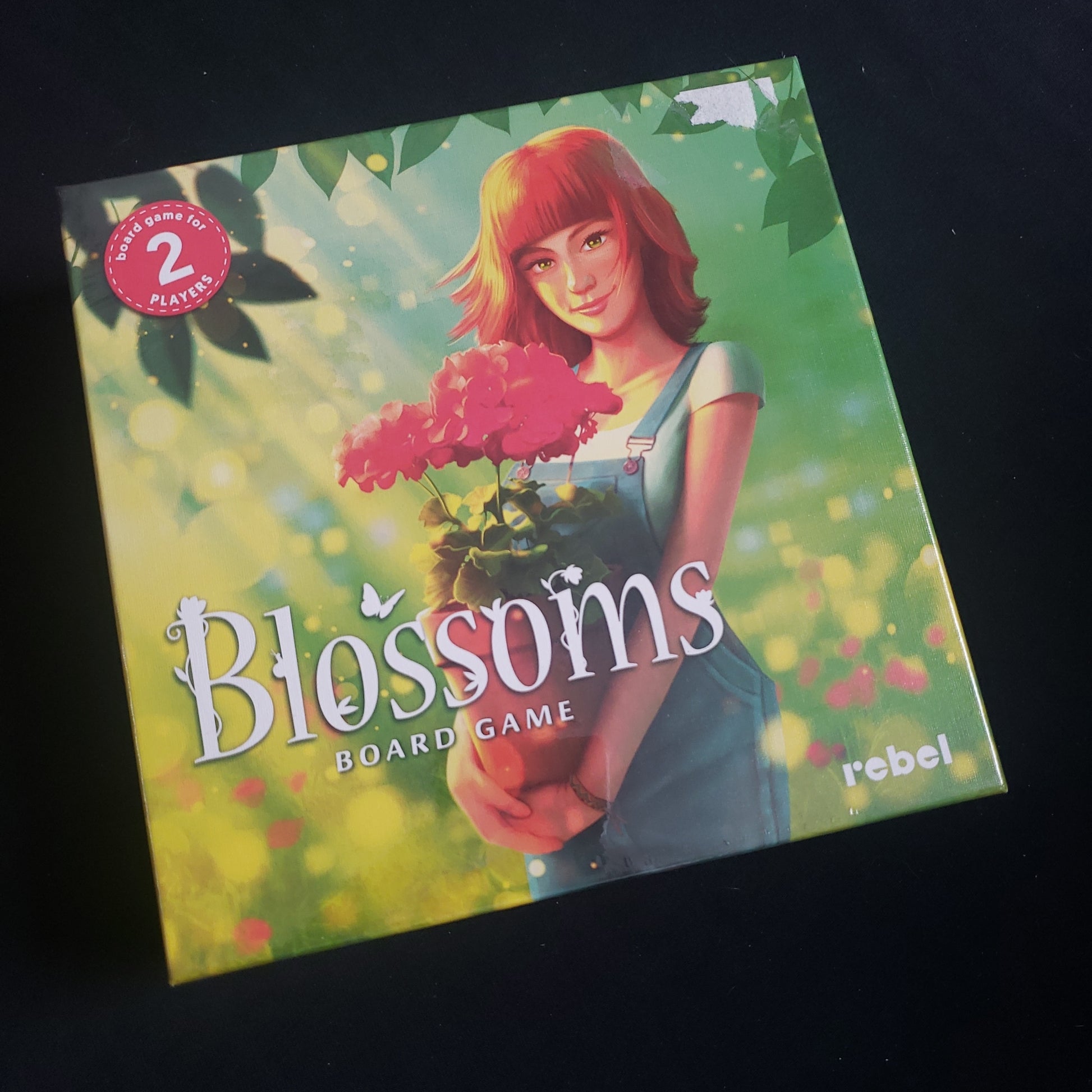 Image shows the front cover of the box of the Blossoms card game