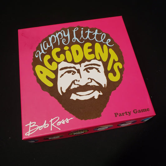 Image shows the front cover of the box of the Bob Ross: Happy Little Accidents board game