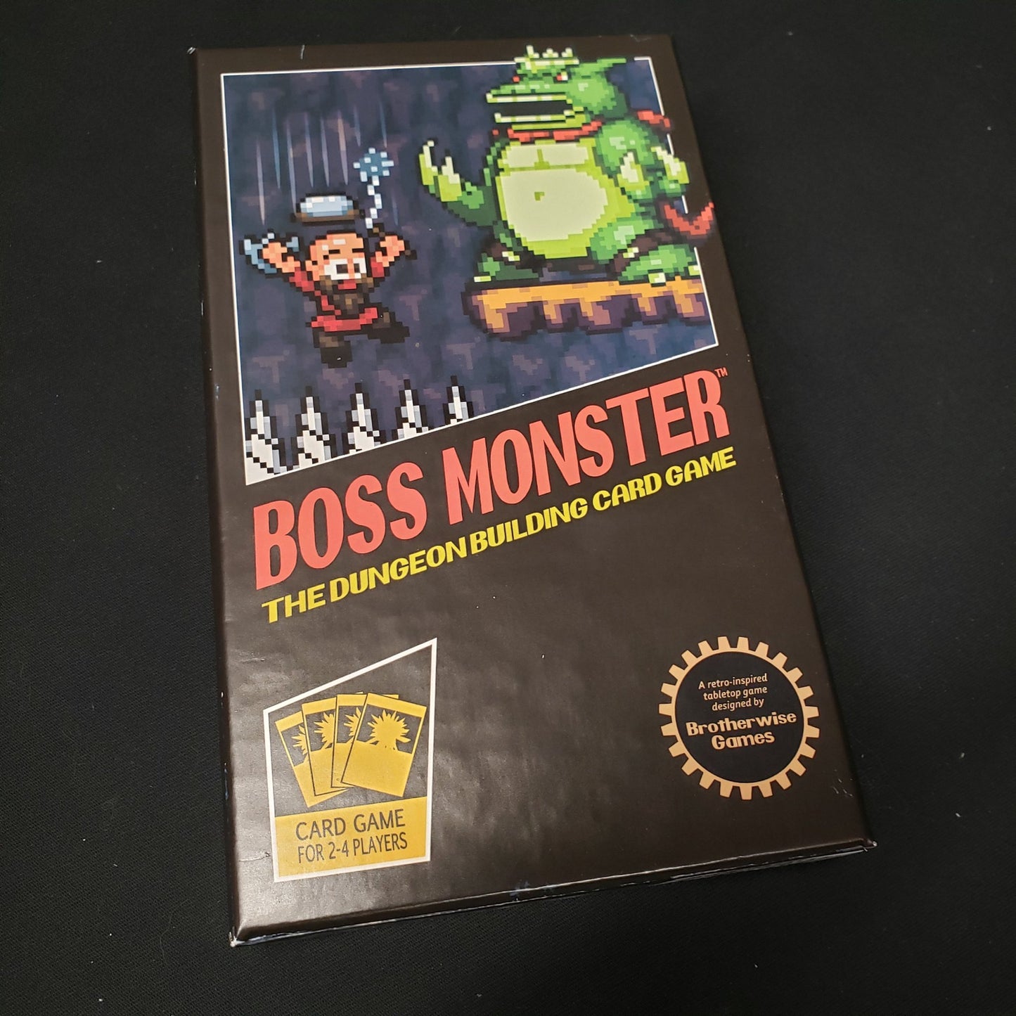 Image shows the front cover of the box of the Boss Monster card game