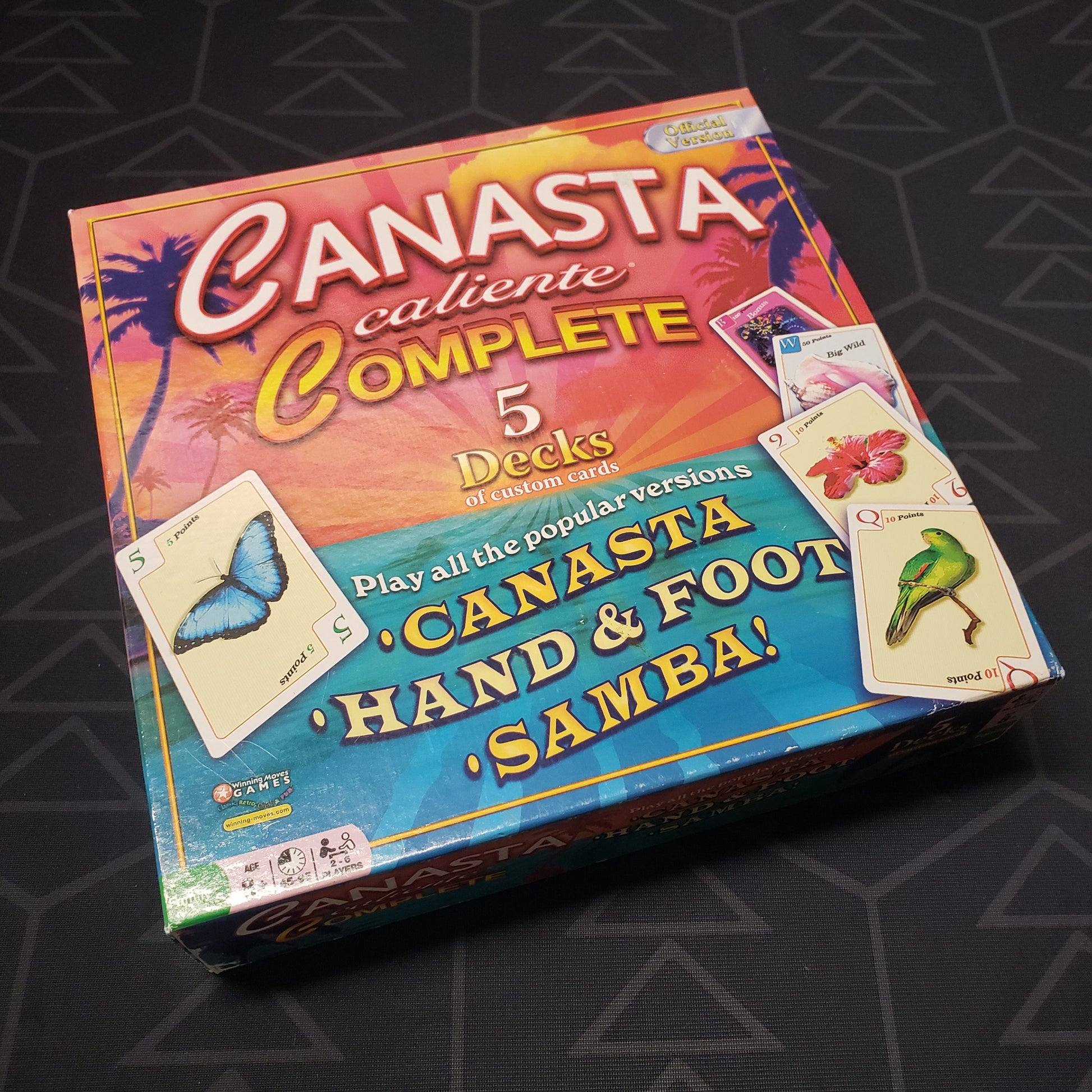 Image shows the front cover of the box for the Canasta Caliente Complete card game